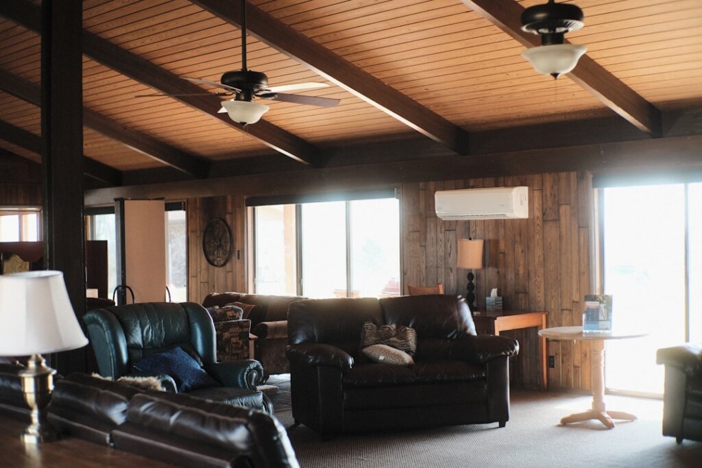 living room with air conditioner and standing fan both running, soft afternoon light, baby sleeping on sofa