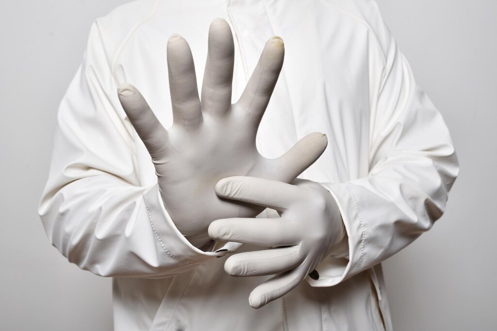 rubber gloves and mask laid next to bleach bottle in bathroom