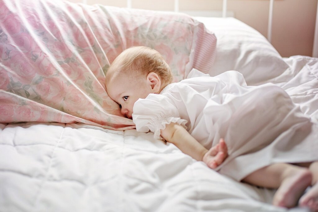 child sleeping peacefully in bed with lavender spray bottle on bedside table