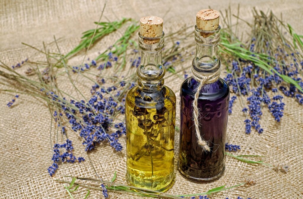 lavender essential oil dropper on wooden surface with purple flowers