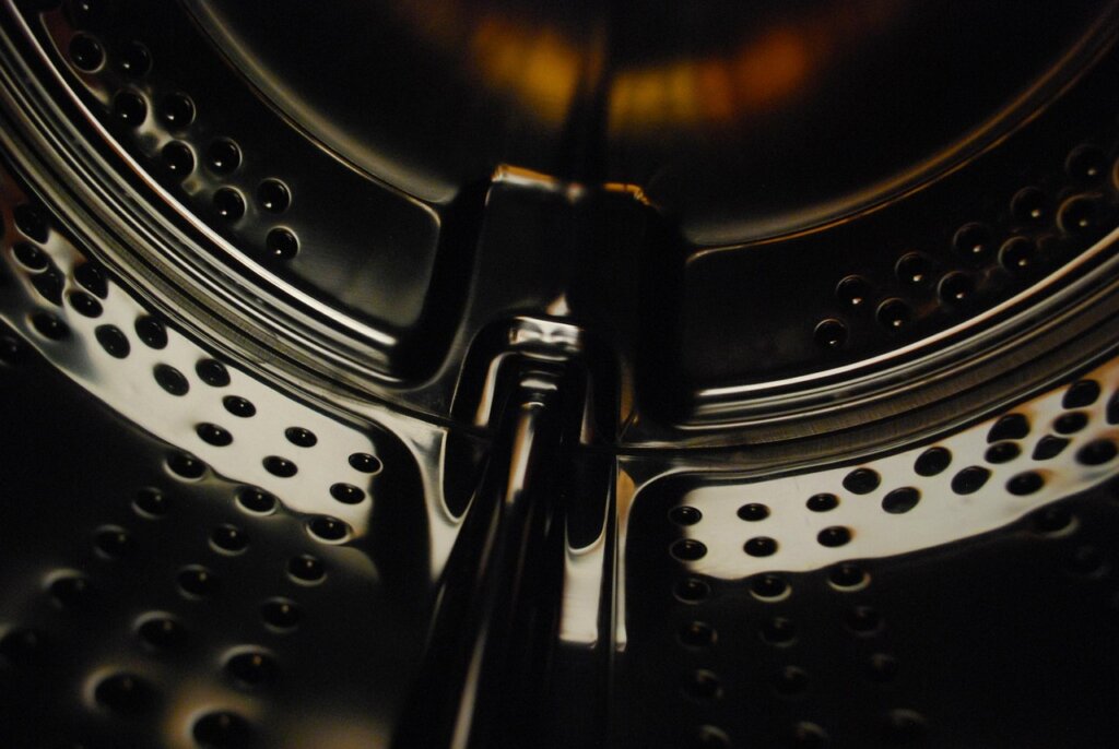 hand wiping inside of washing machine drum with microfiber cloth
