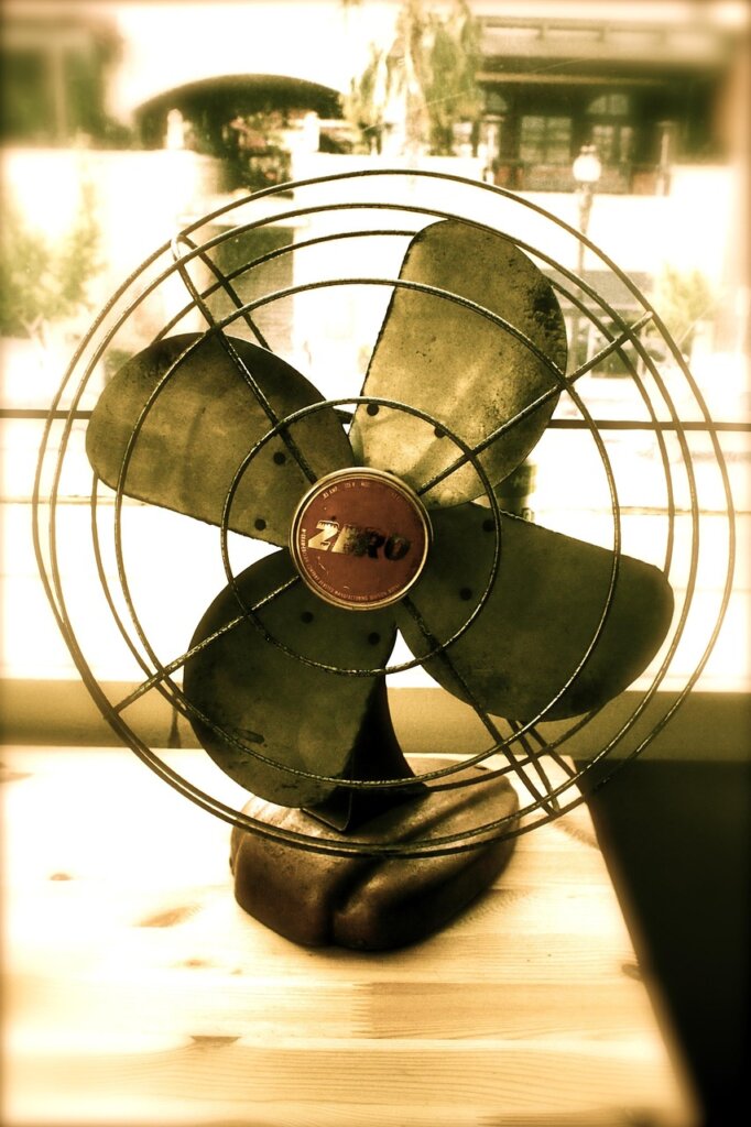 electric fan blowing air toward hanging duvet on balcony