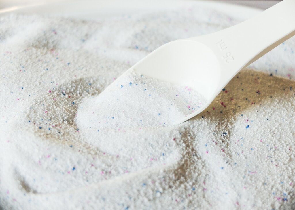 laundry detergent being poured on stained fabric area before washing