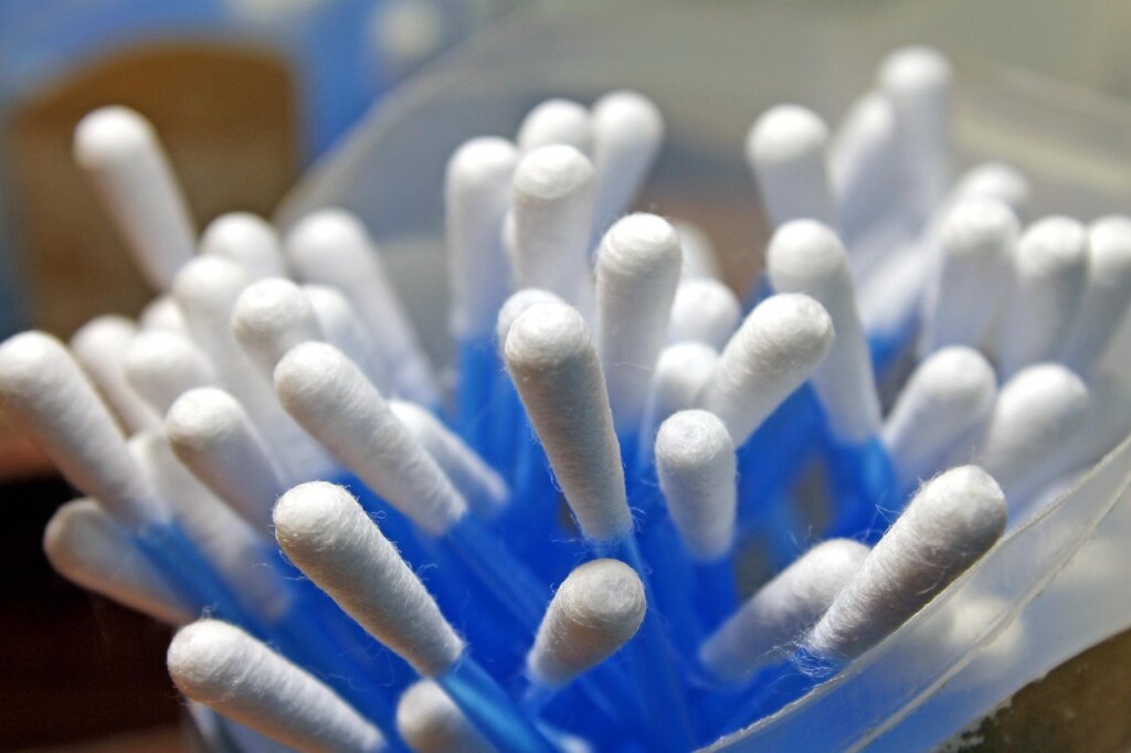 rubbing alcohol being applied with cotton swab on fabric to remove gum residue