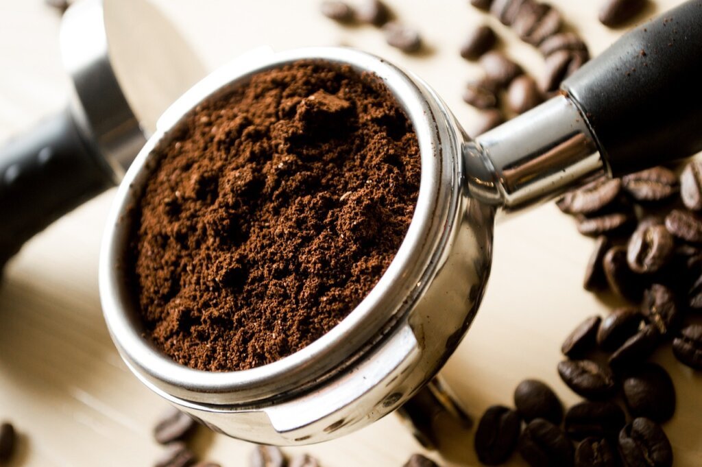 dried coffee grounds in small container with lid off, kitchen background
